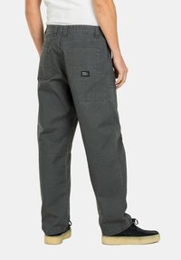Gray cotton cargo pants with side pockets, heavy stitching, and a label on the back pocket. Loose fit design and straight leg cut.