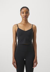 Camiseta negra corta sin mangas con finas tirantes que presenta un escote en forma de V. Textura suave, diseño minimalista, ideal para combinar con prendas de cintura alta.