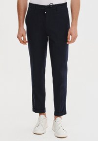 Granatowe spodnie wykonane z lekkiego materiału, z prostymi nogawkami. Posiadają elastyczny pas ze sznureczkiem, mankiety u dołu oraz boczne kieszenie.