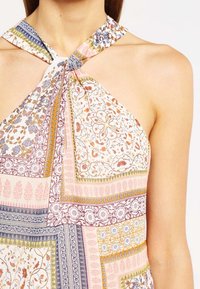 Vestido halter multicolorido con diseño de patchwork, que presenta patrones florales y geométricos, y una tela ligera.