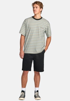 T-shirt à manches courtes rayé dans des teintes de vert clair, noir et crème. Il présente un col rond et une poche sur la poitrine, associé à un short noir.
