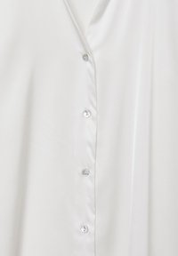 Blusa in satin bianco con scollatura a V, sei bottoni iridescenti lungo il davanti e una texture liscia e lucida.