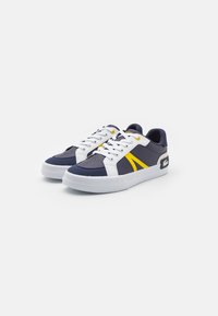 Zapatillas azul marino con acentos en blanco y amarillo, con un upper de cuero liso, cierre de cordones y una suela de goma texturizada.
