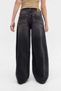 Jeans s širokými nohavicami v tmavo sivej farbe. Obsahuje dve zadné vrecká s žltým prešitím a kožený štítok na páse. Mäkkučká, textúrovaná tkanina.