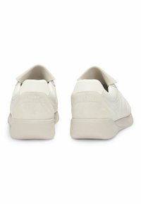 Baskets en cuir blanc avec textures lisses et en daim, un petit talon rembourré, et "HUGO" embossé à l'arrière. Design minimaliste aux lignes épurées.