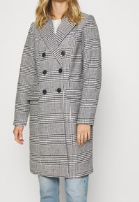 Doppelreihiger Mantel im schwarz-weiß karierten Hahnentritt-Muster mit großen Knöpfen, Reverskragen und Seitentaschen.