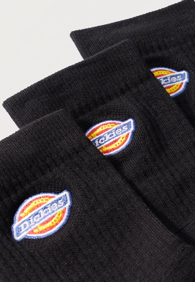 Three black ribbed socks arranged diagonally, each featuring a stitched multicolor Dickies logo near the top cuff.