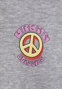 Šedé tričko s barevným potiskem, na kterém je text "Urban Classics" a symbol míru v červené, žluté a fialové barvě.