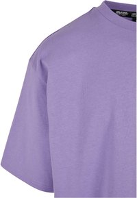 Short-sleeve t-shirt in light purple cotton, featuring a smooth texture and a crew neckline, with visible stitching along the hem.