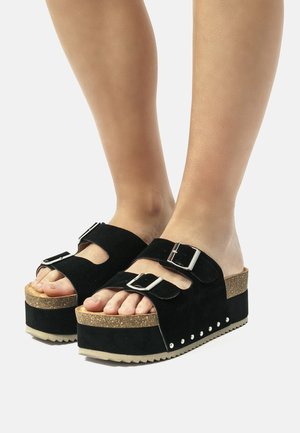 Sandalias de plataforma de ante negro con dos correas ajustables, plantilla de corcho y suela de goma texturizada. Notable herrajes de plata y tachuelas laterales.