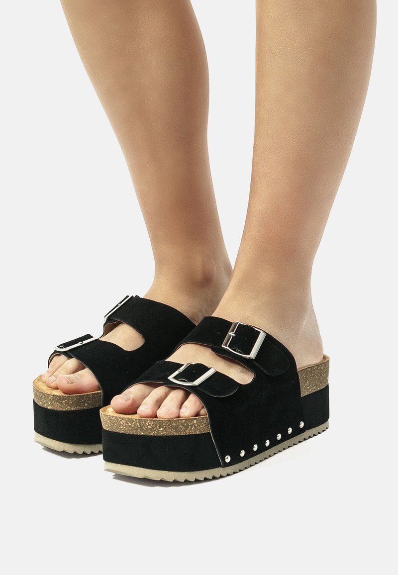 Sandalias de plataforma de ante negro con dos correas ajustables, plantilla de corcho y suela de goma texturizada. Notable herrajes de plata y tachuelas laterales.