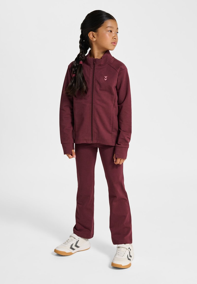 Vinröd zipjacka och matchande byxor i mjukt tyg. Har en diskret logotyp på bröstet, långa ärmar och figursydd siluett.