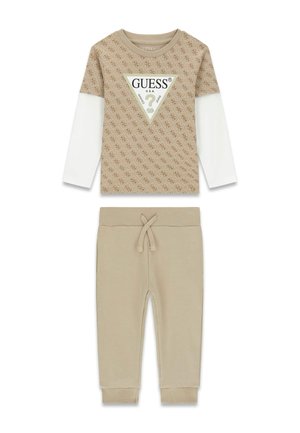 Beiges Langarmshirt mit weißen, geschichteten Ärmeln und Guess-Logo, kombiniert mit passenden beigen Kinderhose mit Kordelzug.