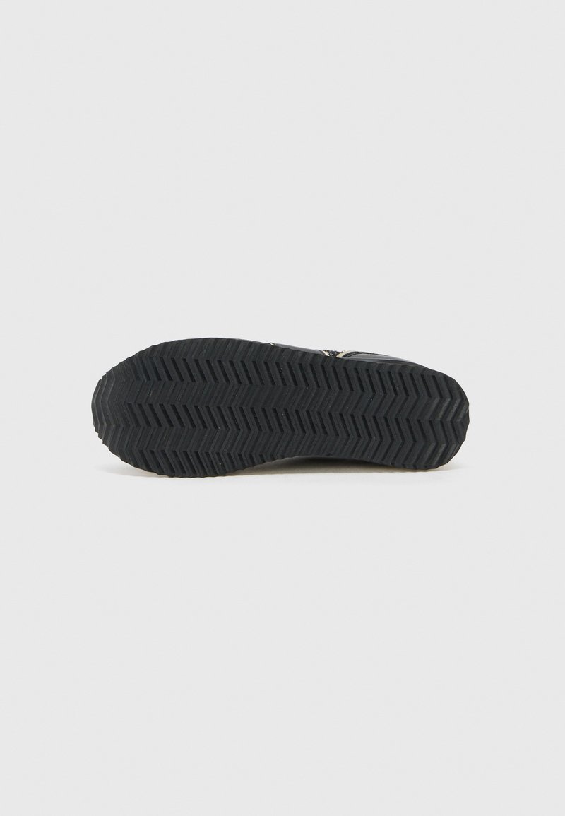 Semelle de chaussure en caoutchouc noir avec motif en chevrons, présentant une surface texturée et une légère élévation au niveau du talon.