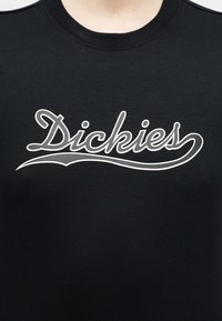 Μαύρο πουκάμισο με στρογγυλή λαιμόκοψη και λευκή καλλιγραφική επιγραφή "Dickies" στο κέντρο του στήθους.