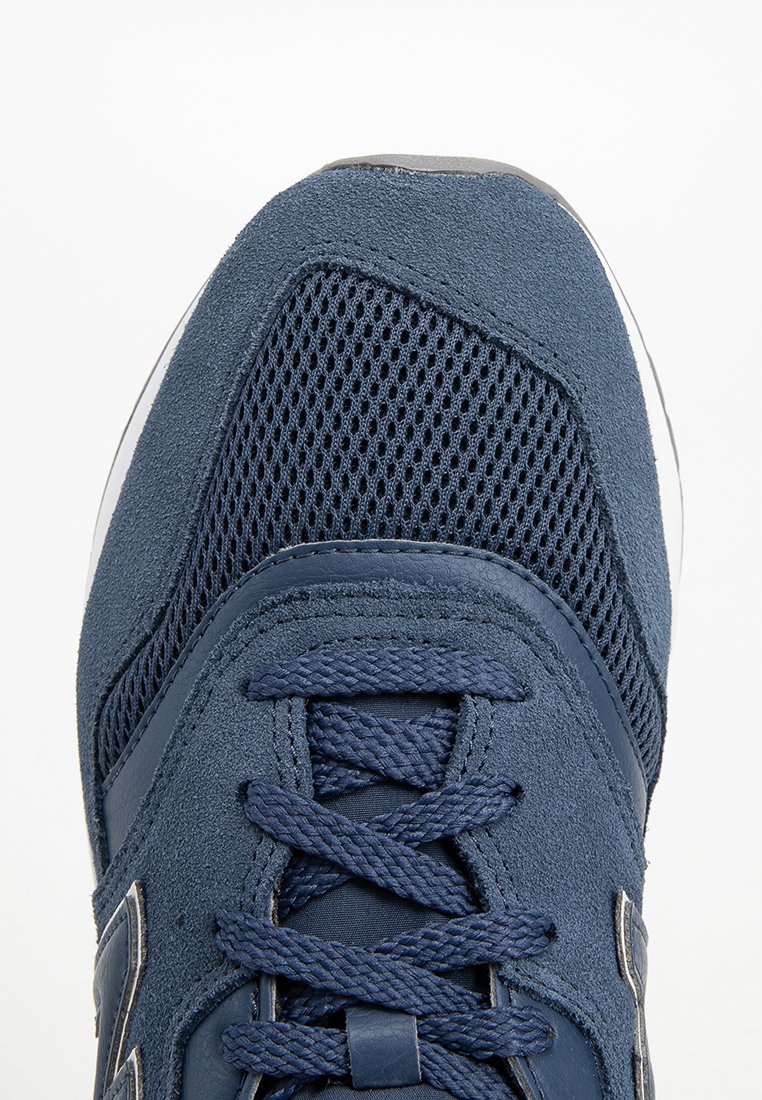 Marine sneaker met een combinatie van mesh- en suède materialen, gestructureerde veters en een gevoerde zool met een slank ontwerp.