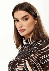 Brown and cream patterned high-neck top with swirling lines. Smooth fabric, fitted design, with short, gathered sleeves.