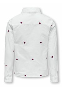 Camisa blanca con cuello, adornada con corazones burdeos bordados dispersos. Mangas largas con puños de botón. Textura suave.