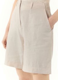 Beige linen shorts with side pockets, featuring a straight cut and a smooth texture. The fabric has a subtle sheen and tailored finish.