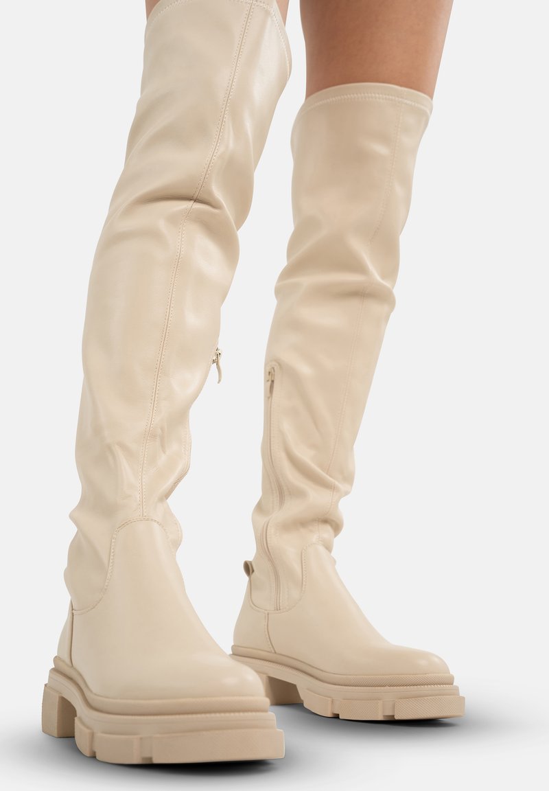 Botas de cuero beige hasta la rodilla con un diseño holgado, punta redondeada y suela de plataforma gruesa. Cremalleras laterales para facilitar el uso.