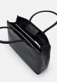 Czarna skórzana torba typu tote z podwójnymi uchwytami, wyposażona w komorę na zamek i gładką fakturę. Minimalistyczny design, przestronne wnętrze.