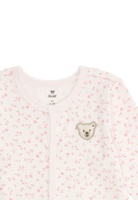 Babyspeeltje in lichtroze stof met kleine bloemenprint. Heeft een berenborduursel op de borst en knoopsluiting aan de voorkant.