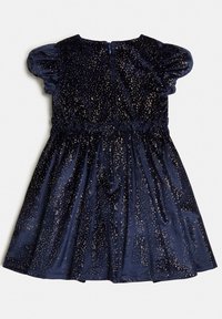 Marinblå sammetklänning med korta puffsärmar, insnörad midja och spridda guldprickar. Slät textur, knälång design. Dragkedja i ryggen.