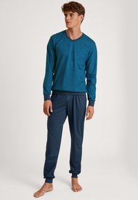 Long-sleeve blue shirt with a geometric pattern, paired with navy pants. The shirt has a V-neck and ribbed cuffs, while pants have elastic hems.