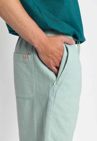 Lichtgroene, gestructureerde broek met een zijrits zak. Gepaard met een donkergroene shirt met korte mouwen, met een ontspannen pasvorm.