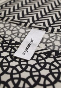 Motivi geometrici neri su un tessuto chiaro con una trama intrecciata; un'etichetta con "sofa concept" è visibile nell'angolo in basso a destra.