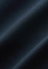 Dunkelblauer Stoff mit einer strukturierten Webart, die subtile Rillen und glatte Oberflächenvariationen zeigt, die ein reiches, tiefes Erscheinungsbild erzeugen.