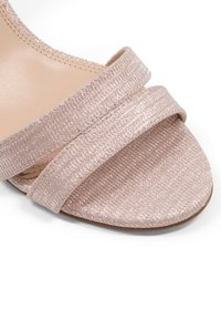 Sandale à glissière rose gold avec deux brides texturisées, présentant un subtil éclat et une semelle intérieure lisse couleur nude. Semelle plate avec un bout arrondi.