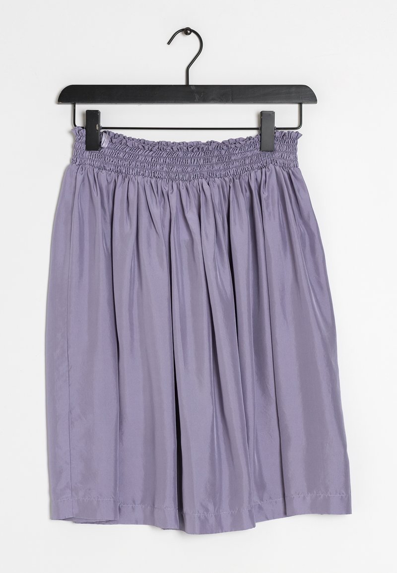 Jupe plissée violet clair avec ceinture élastique suspendue à un cintre noir sur fond blanc.
