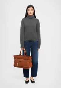 Gray turtleneck sweater, high-waisted blue jeans, and a brown suede tote bag with a belt detail and key charm, paired with black flats.