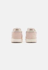 ASICS athletic shoes with a soft pink suede upper, cream mesh accents, and a textured rubber sole. Logo displayed on the heel.