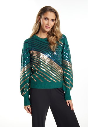 Grøn trøje med glitrende pailletter i diagonale striber af bronze og blå. Har rund halsudskæring og lange, puffede ærmer.