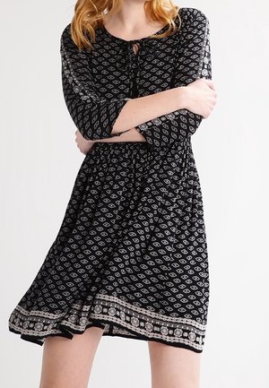 Robe noire avec des manches trois-quarts, dotée d'un motif en diamants, taille cintrée et ourlet décoratif. Tissu texturé avec une coupe décontractée.