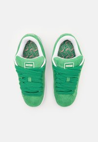 Grønne semskede sneakers med teksturerte grønne snører, hvite detaljer og en mønstret innersåle med logo på tunge.