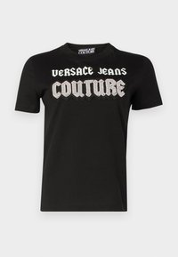 Must mustrine T-särk, millel on rinnas julgete, valgete, tekstuursete tähed "VERSACE JEANS COUTURE" ja ehtedetailid. Lühikesed varrukad.