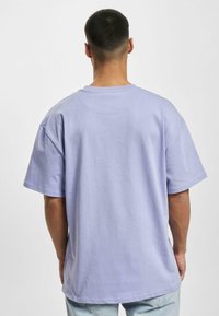 Lilla bomulds t-shirt med korte ærmer, runde halsudskæring og en afslappet pasform, med en glat tekstur og ingen synlige mønstre eller dekorative elementer.