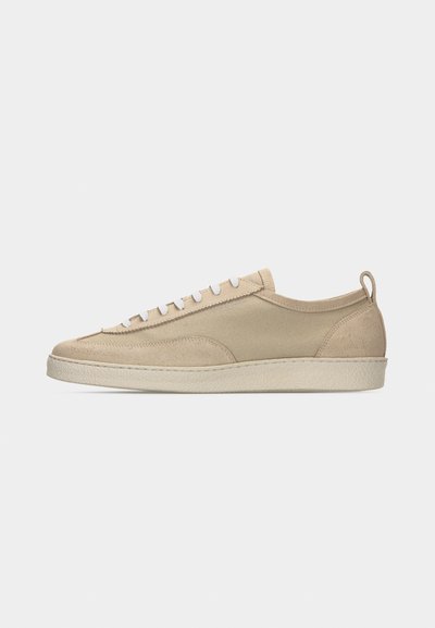 Beiger Sneaker mit niedriger Schafthöhe, Obermaterial aus Stoff und Wildleder, weißen Schnürsenkeln, Gummisohle und Fersenlasche, seitlich auf weißem Hintergrund dargestellt.