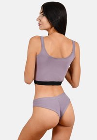 Lichtpaarse crop top met een zwarte band, gecombineerd met bijpassende lichtpaarse onderbroekjes. Zacht katoen, slim fit ontwerp en minimale stikdetails.