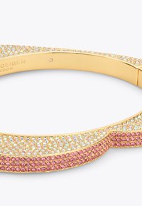 Złocona bransoletka z iryzującym wzorem kryształu na górze i różowymi kryształowymi akcentami wzdłuż podstawy. Gładka powierzchnia, zaokrąglony kształt.