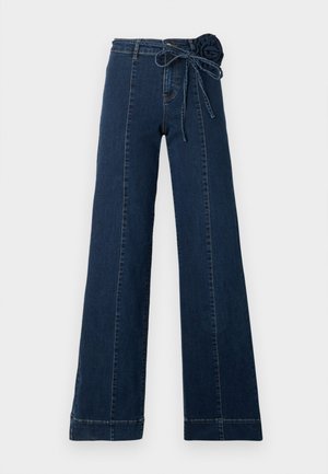 Jeansi din denim albastru închis cu design cu picior larg, prevăzuți cu o trandafiră decorativă din țesătură în talie și o panglică legată. Detalii de cusături de-a lungul picioarelor.