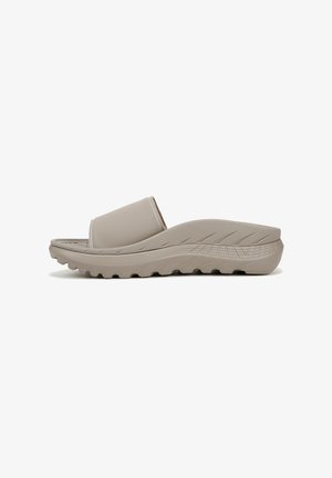 Beige schuif sandaal met een gladde bovenkant en een dikke, gevormde rubberen zool met een gestructureerd patroon voor grip. Laag profiel ontwerp.