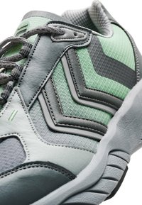 Träningsskor med en texturerad övre del i grått och mintgrönt, med detaljfärger i chevronmönster, snörning och vadderad krage. Gummisula.