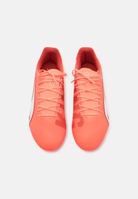 Bright coral athletic shoes featuring a smooth, synthetic upper, thin laces, and a sleek, low-profile design. White accent on the side.