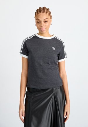 Camiseta atlética gris con ribetes blancos en el cuello y las mangas, que presenta tres rayas blancas en los hombros y un pequeño logo.