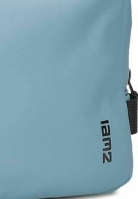 Blauw stoffen tas met een glad oppervlak, vierkante vorm en zwarte merkaanduiding. Bevat een zijbandbevestiging voor draaggemak.