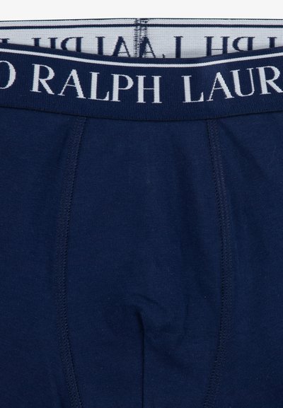 Tamno plave pamučne gaće s bijelim pojasom na kojem je reljefno označeno "RALPH LAUREN". Glatka tekstura, standardni kroj i bez dodatnih uzoraka.